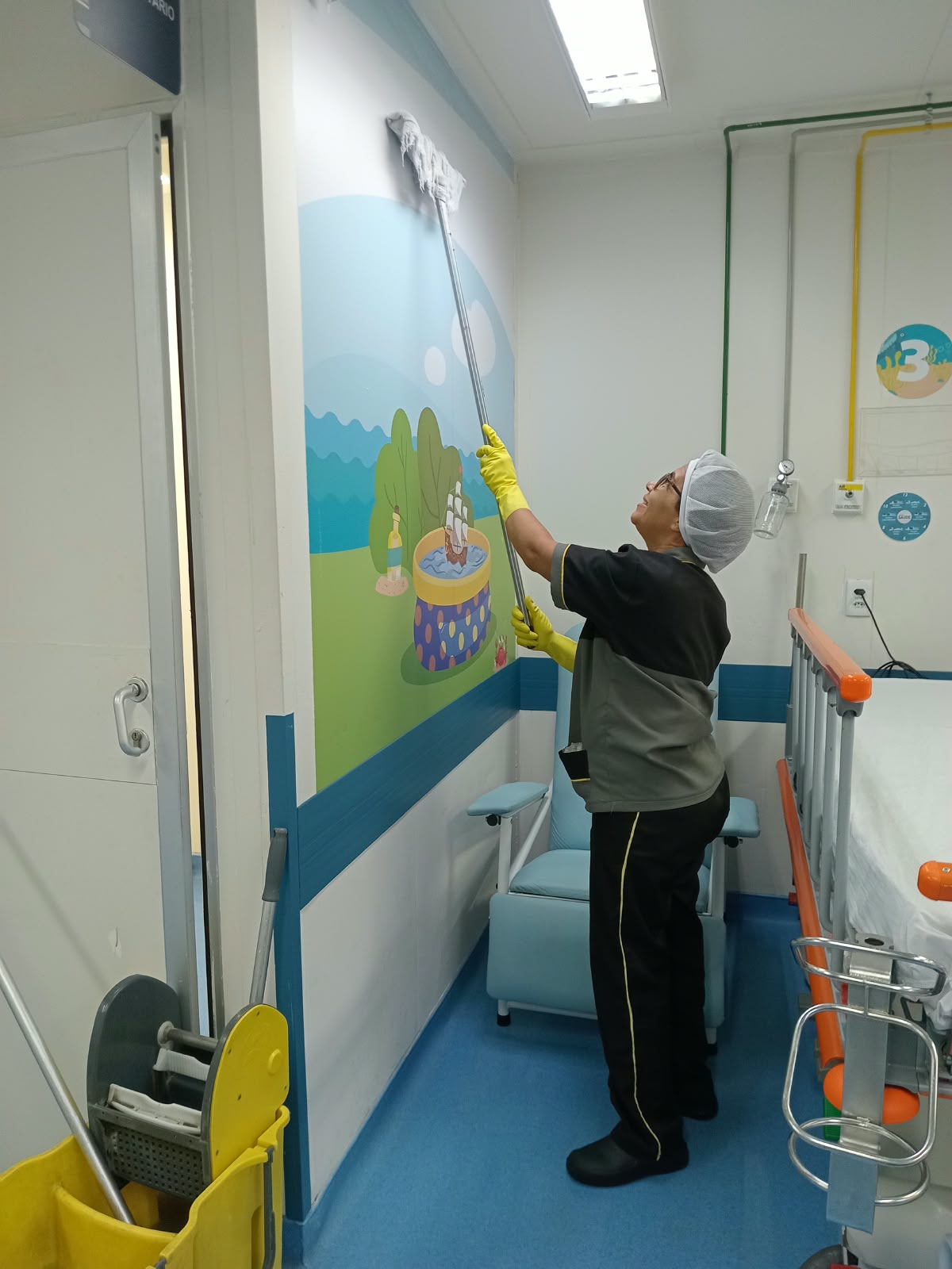 Colaboradora Galileu organizando materiais de limpeza em prateleiras de unidade de saúde
